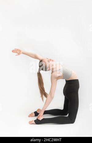 Une fille pratique le yoga à Camel pose sur fond blanc.Ustrasana.Une jeune femme instructeur de yoga exécute l'asana Banque D'Images