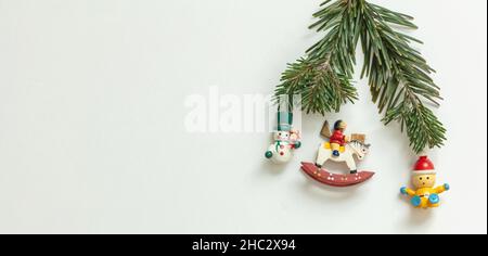 Modèle de carte de vœux de Noël pour le nouvel an.Jouets vintage en bois et branche de sapin frais sur fond blanc, espace de copie. Banque D'Images