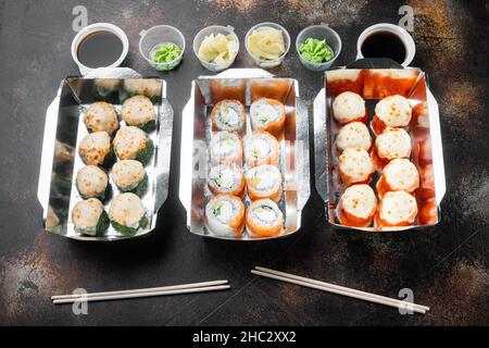 Petits pains à sushi dans un ensemble de récipients à emporter, sur fond rustique foncé Banque D'Images