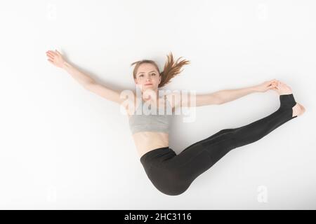 La jeune femme est engagée dans la gymnastique.Développement de la flexibilité.Asanas en yoga.Belle fille mince ne hatha yoga sur fond blanc. Banque D'Images