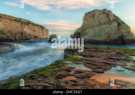 Une scène côtière à couper le souffle avec l'imposante pile de mer Shark fin s'élevant de l'océan à Shark fin Cove, Davenport, Californie, au coucher du soleil. Banque D'Images