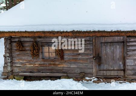 Bains besoms accrochés sur le mur de la maison de bains de Vidzeme avec maison de logement sous la neige Banque D'Images