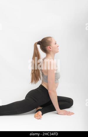 Portrait d'une magnifique jeune femme pratiquant le yoga.Fille fait l'étirement sur fond blanc.Cadre vertical Banque D'Images