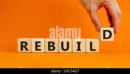 Reconstruire et construire le symbole.Le mot concept reconstruire sur des cubes en bois.Belle table orange, fond orange, espace de copie.Main d'homme d'affaires.Entreprise Banque D'Images