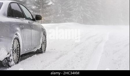 Voiture argentée garée sur une route enneigée, vue détaillée depuis l'arrière-plan, arbres flous arrière-plan vide d'espace pour le texte du côté droit Banque D'Images