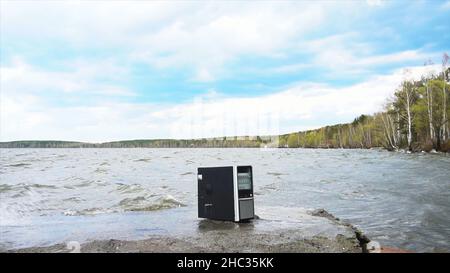 Concept de la liberté de la dépendance informatique - l'homme brise l'unité système d'un ordinateur avec un hummer à l'extérieur, lac avec fond de forêt.Homme en colère déstro Banque D'Images