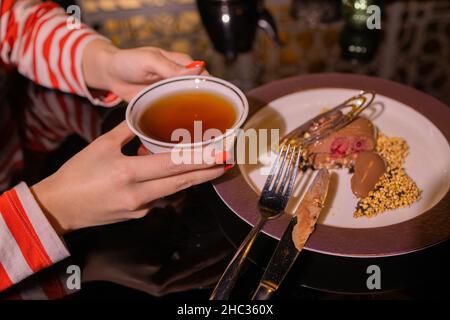 La jeune femme sur le canapé et avec du thé de sauge sur la main Banque D'Images