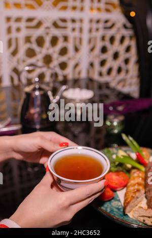 La jeune femme sur le canapé et avec du thé de sauge sur la main Banque D'Images