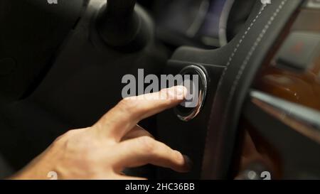 Gros plan pour le conducteur de voiture démarrage du moteur du véhicule moderne, concept de technologies modernes.Un doigt de l'homme appuie sur la touche étoile, arrêter le moteur. Banque D'Images