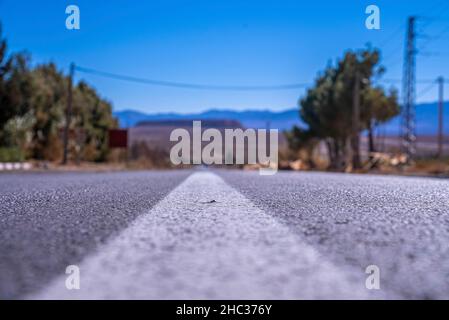 Route asphaltée droite avec marquage de surface blanc contre les montagnes en arrière-plan Banque D'Images