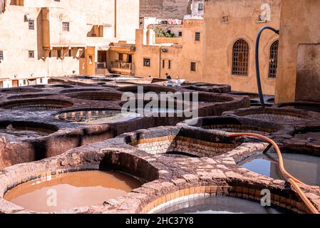 De l'eau teint remplit les réservoirs dans une tannerie vide contre l'ancien bâtiment résidentiel Banque D'Images