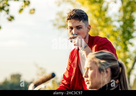 Homme buvant le thé d'un thermo près de t femme dans un parc Banque D'Images