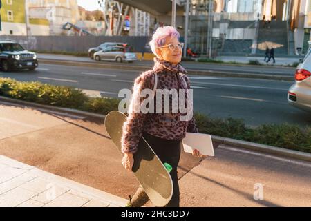 Italie, femme à la mode avec planche à roulettes et tablette numérique en ville Banque D'Images