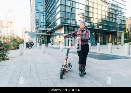 Italie, femme à la mode avec scooter de poussée en ville Banque D'Images