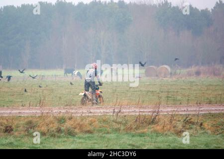 Un cycliste à moteur (motard) qui conduit sa moto tout-terrain le long d'une piste en pierre boueuse sur Salisbury Plain, Wiltshire Banque D'Images