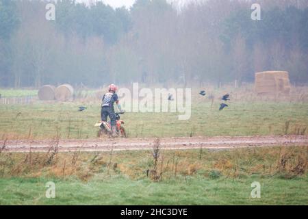 Un cycliste à moteur (motard) qui conduit sa moto tout-terrain le long d'une piste en pierre boueuse sur Salisbury Plain, Wiltshire Banque D'Images