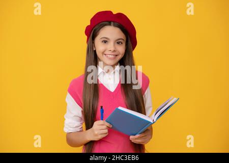 bonne adolescente en béret français, en train de faire des notes dans le bloc-notes ou le bloc-notes de l'agenda, l'école Banque D'Images