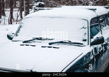 Vieille voiture couverte de neige, conduite par temps neigeux Banque D'Images