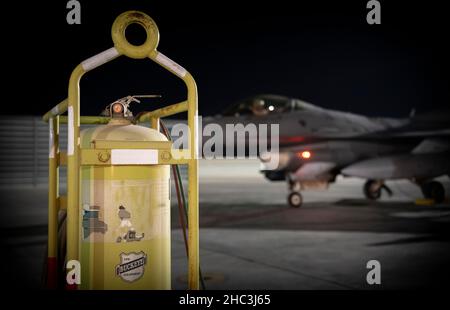 Un faucon de combat F-16 de la Force aérienne des États-Unis est stationné près d'un extincteur d'incendie en ligne pendant l'opération Agile Spartan à la base aérienne d'Al Udeid, Qatar, le 20 décembre 2021.L’Escadron de maintenance expéditionnaire du 379th e Escadron a facilité le ravitaillement en carburant à ciel ouvert, ce qui permet à l’aéronef de atterrir, de se ravitailler, de subir une inspection rapide et de se retirer le plus rapidement possible dans le but d’accroître la capacité de dissuasion stratégique et la résilience du pilote.(É.-U.Photo de la Force aérienne par le premier Airman Jacob Dastas) Banque D'Images