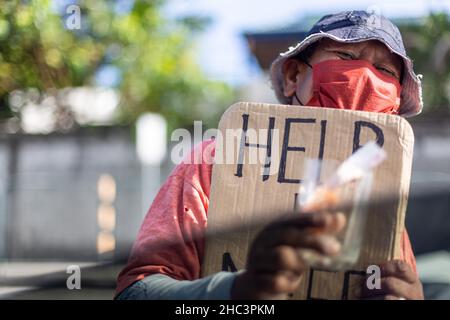 Personne sans-abri qui demande de l'argent aux conducteurs sur une route très fréquentée à Makati, aux Philippines Banque D'Images