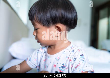 Un petit garçon dorme sur son lit le matin, se réveille avec une couverture blanche Banque D'Images