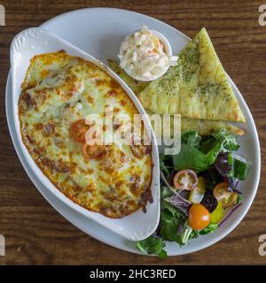 Vue de dessus de la lasagne au bœuf Aberdeen Angus avec pain plat à l'ail - salade et coleslaw Banque D'Images