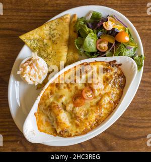 Vue de dessus de la lasagne au bœuf Aberdeen Angus avec pain plat à l'ail - salade et coleslaw Banque D'Images