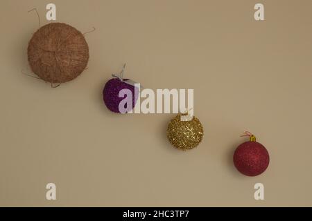 Décorations de noix de coco et de Noël de différentes couleurs sur fond beige.Pose plate minimale. Banque D'Images