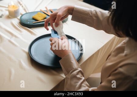 Vue rapprochée en grand angle d'une femme artisanale méconnue qui prend une belle bougie blanche d'auteur en moule en silicone. Banque D'Images