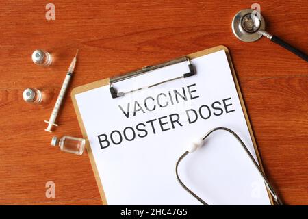Vue de dessus du stéthoscope, flacon en verre de 3 flacons, seringue et presse-papiers avec texte DOSE DE RAPPEL DU VACCIN Banque D'Images