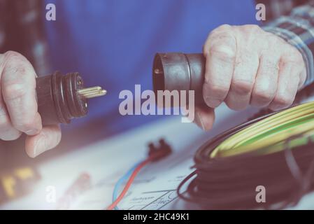 Mains d'électricien tenant les fiches électriques Banque D'Images