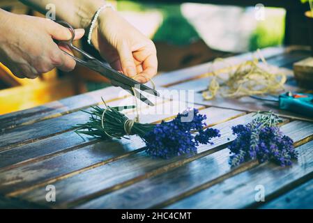 Femme créant un bouquet de fleurs naturelles de lavande.Fleuriste au travail sur une table en bois.Lier les fleurs de lavande Banque D'Images