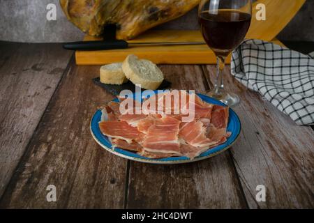 assiette de jambon ibérique espagnol nourri au gland en premier plan avec pain et vin hors-d'œuvre typiquement espagnol Banque D'Images