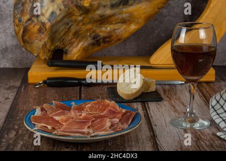 assiette de jambon ibérique espagnol nourri au gland en premier plan avec pain et vin hors-d'œuvre typiquement espagnol Banque D'Images