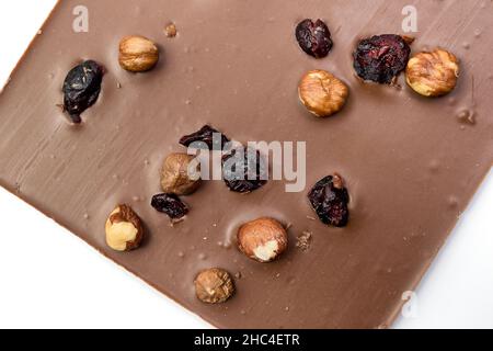 Chocolat au lait fait à la main avec noisettes, raisins secs et fruits secs sur fond blanc.Mise au point sélective Banque D'Images