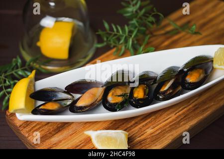 Assiette blanche avec moule dans l'évier et tranche de citron sur le bureau en bois par le dessus Banque D'Images