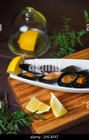 Assiette blanche avec moule dans l'évier et tranche de citron sur le bureau en bois par le dessus Banque D'Images