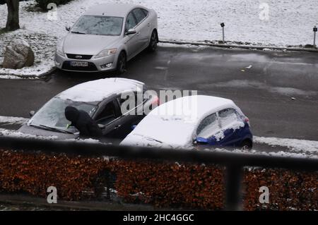 Copenhague/Danemark./24 décembre 2021/ une femme enlève la neige de la fenêtre avant de la voiture car la neige météo tombe à Kastrup et le propriétaire enlève la neige du sentier de la capitale danoise Kastrup Copenhague.(Photo..Francis Joseph Dean/Dean Pictures) Banque D'Images