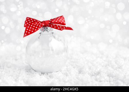 Boule de noël transparente sur la neige.Carte de vœux de Noël ou du nouvel an. Banque D'Images