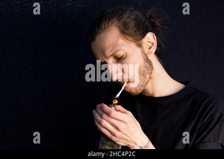 Woodbridge Suffolk UK Mai 08 2020: Un jeune hipster mâle fuyant une cigarette roulée à la main ou une articulation de cannabis Banque D'Images