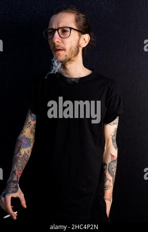 Woodbridge Suffolk UK Mai 08 2020: Un jeune hipster mâle fuyant une cigarette roulée à la main ou une articulation de cannabis Banque D'Images