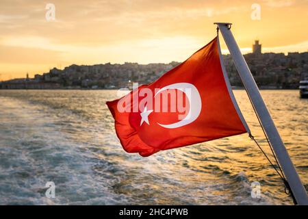 Le drapeau turc flotte dans le vent contre Istanbul Bosporus au coucher du soleil.Le drapeau de la République de Turquie. Banque D'Images