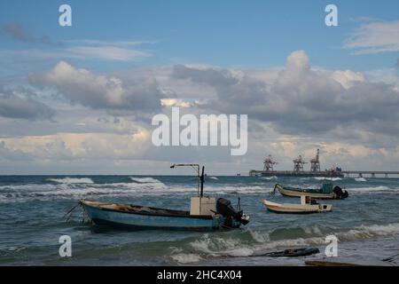 Trois petits bateaux de pêche ancrés à côté d'un quai par une journée d'hiver nuageux. Banque D'Images