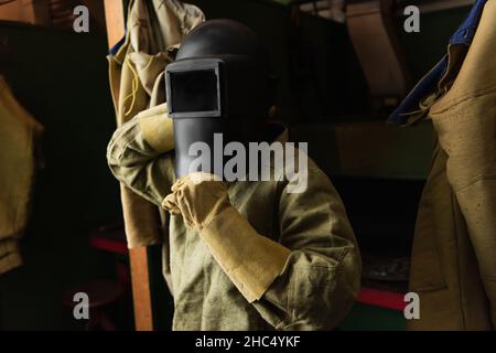 Soudeur en gants portant un masque de protection avec visière en usine Banque D'Images