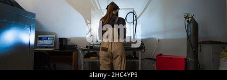 Vue arrière du soudeur dans les combinaisons travaillant près d'une bouteille de gaz en usine, bannière Banque D'Images