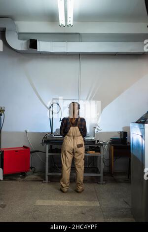 Vue arrière du soudeur dans le masque et la combinaison travaillant en usine Banque D'Images