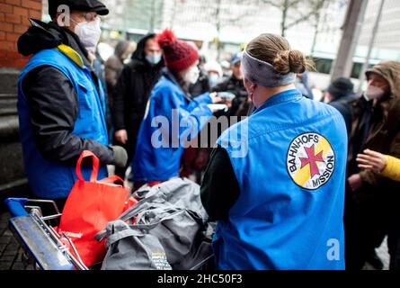 Brême, Allemagne.24th décembre 2021.Les employés de la mission de la gare de Brême distribuent des sacs d'épicerie et des cadeaux aux personnes dans le besoin devant la gare principale.Plusieurs chariots pleins de sacs ont été distribués à environ 100 personnes la veille de Noël.Credit: Hauke-Christian Dittrich/dpa/Alay Live News Banque D'Images