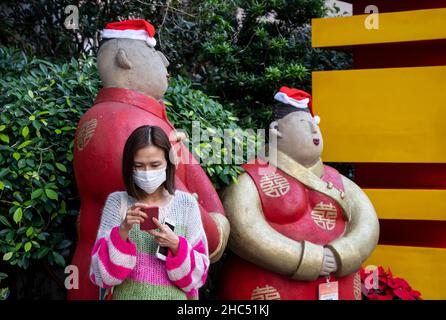 Hong Kong, Chine.24th décembre 2021.Une femme se tient à côté de statues portant des chapeaux du Père Noël à Hong Kong.(Photo par Miguel Candela/SOPA Images/Sipa USA) crédit: SIPA USA/Alay Live News Banque D'Images