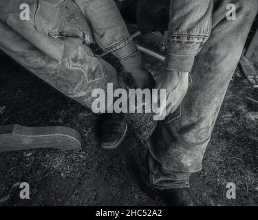 Photo en niveaux de gris d'un homme vêque d'un cowboy assis sur une chaise Banque D'Images