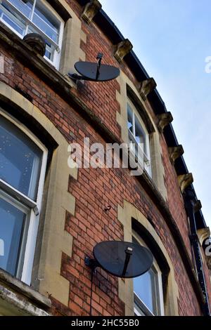 Télévision par satellite recevant des plats sur le côté de la maison en brique, Stroud, Royaume-Uni Banque D'Images